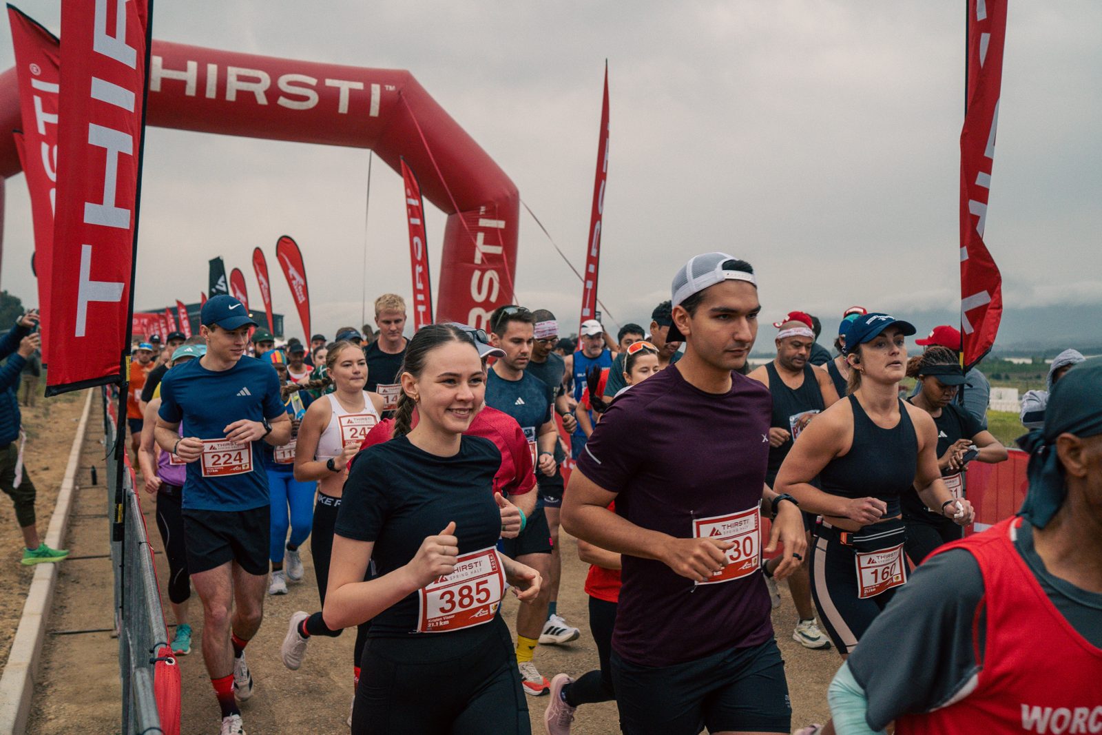Runners starting under the THIRSTI arch